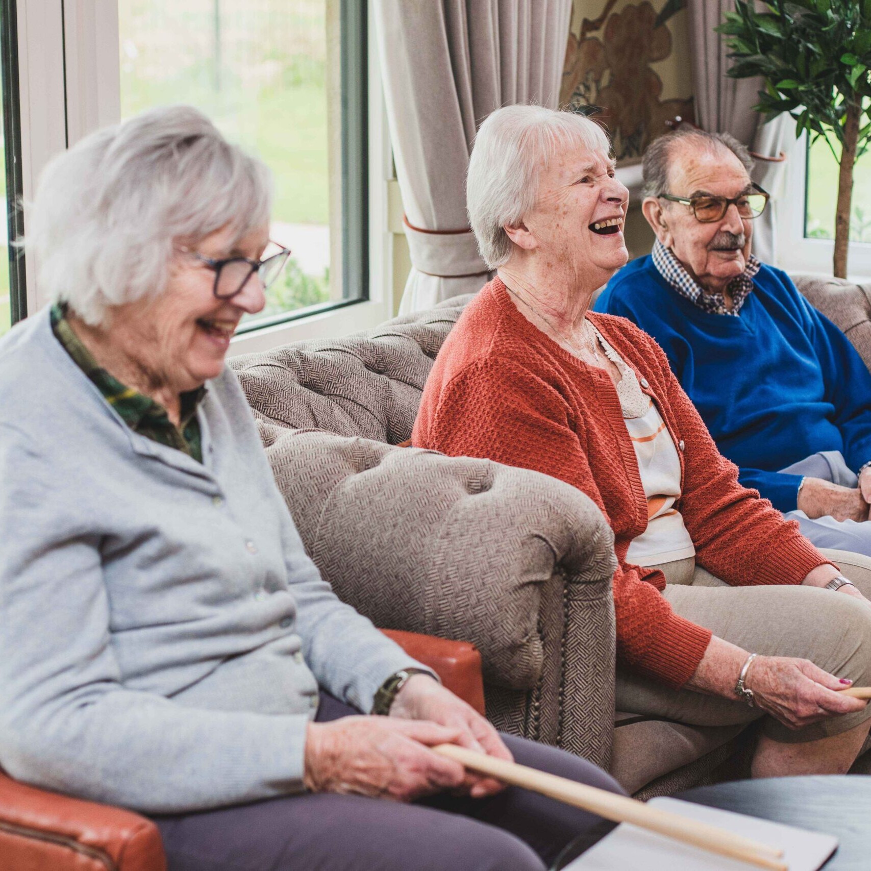 Resident laughing with others in the lounge during a group activity at Esmere Gardens Nursing Home.