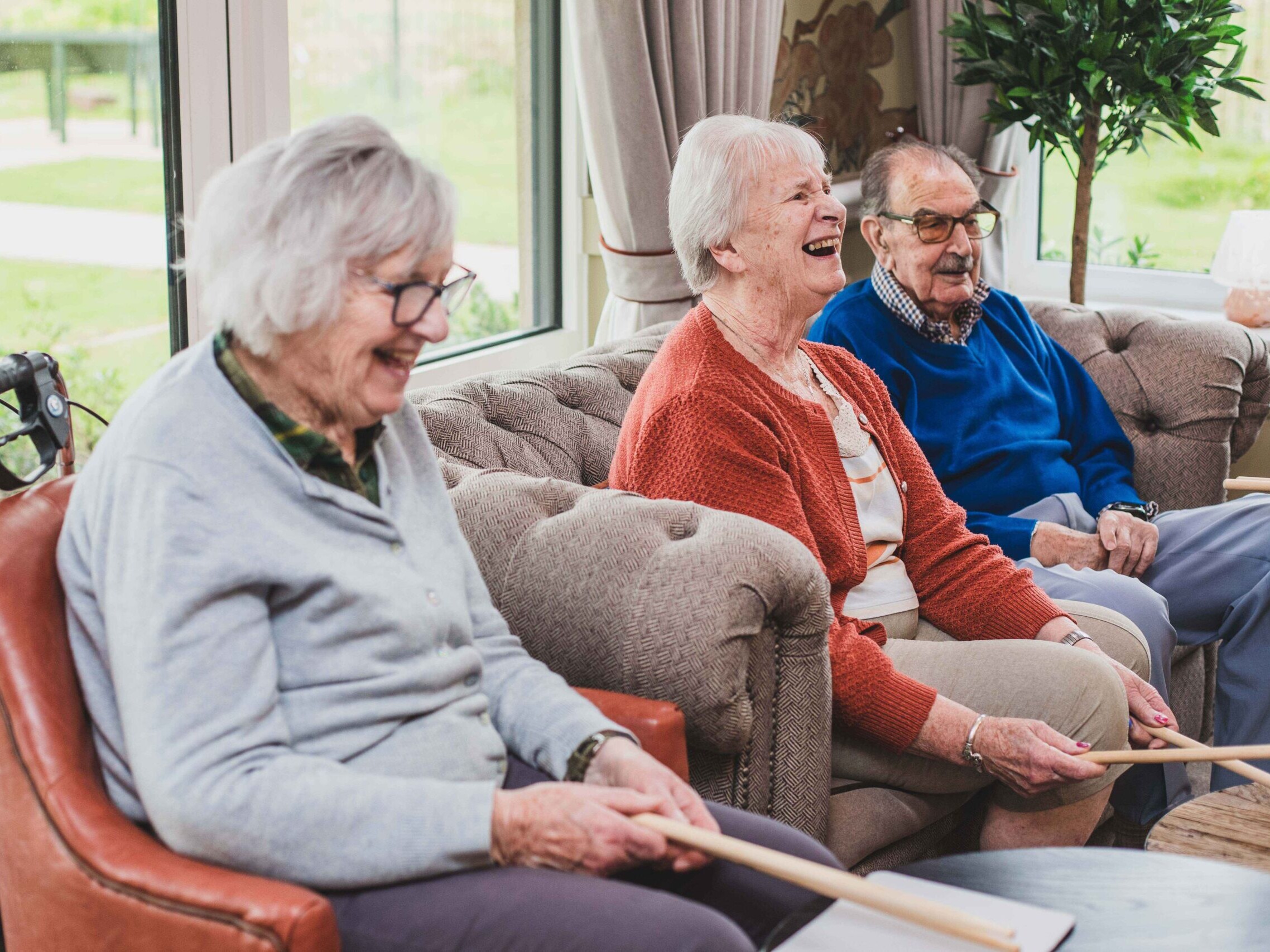 Resident laughing with others in the lounge during a group activity at Esmere Gardens Nursing Home.