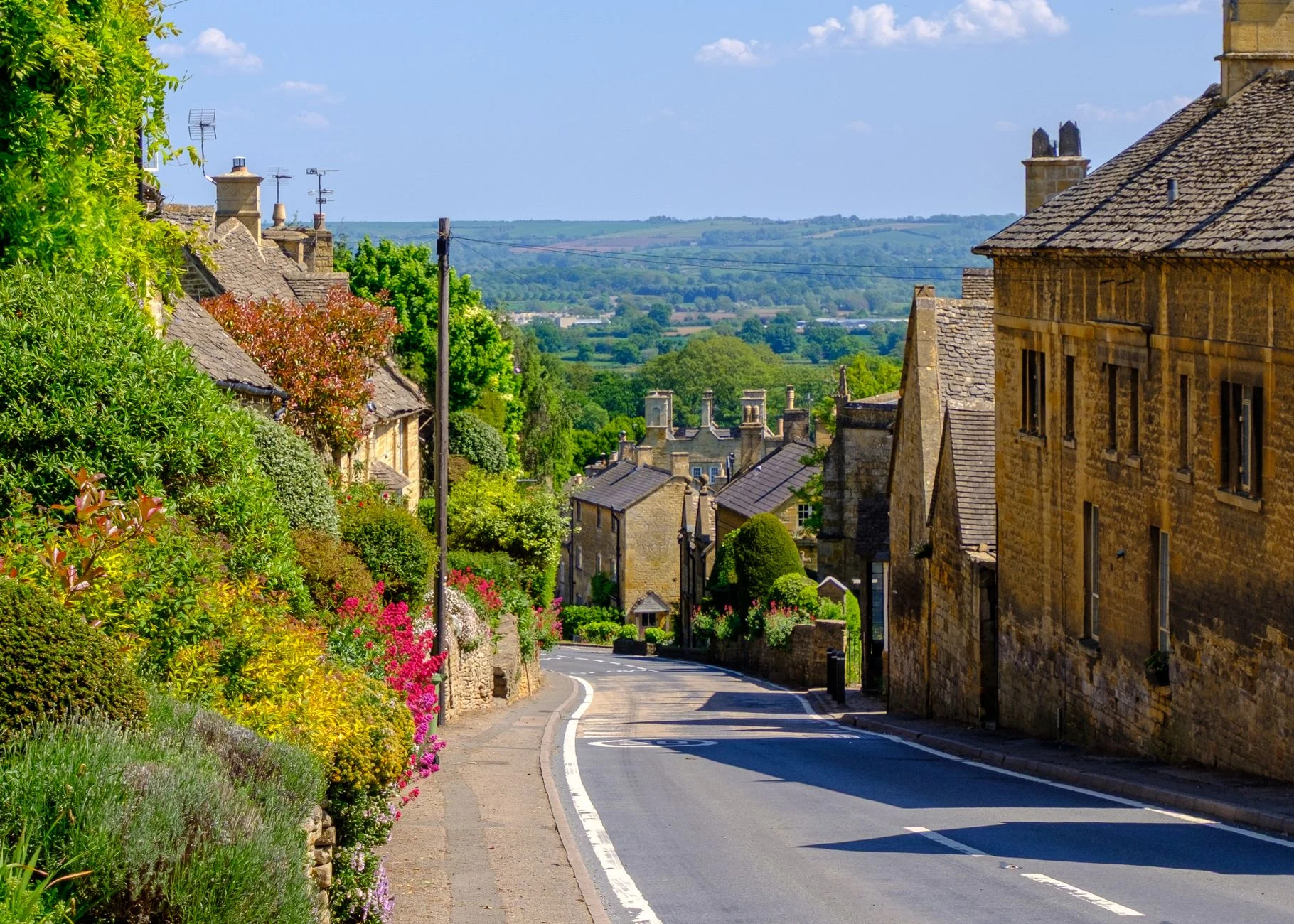 Traditional Cotswold high street with historic stone buildings, independent shops and a welcoming village atmosphere.